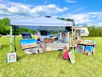 a tent set up in a grassy field with art on display